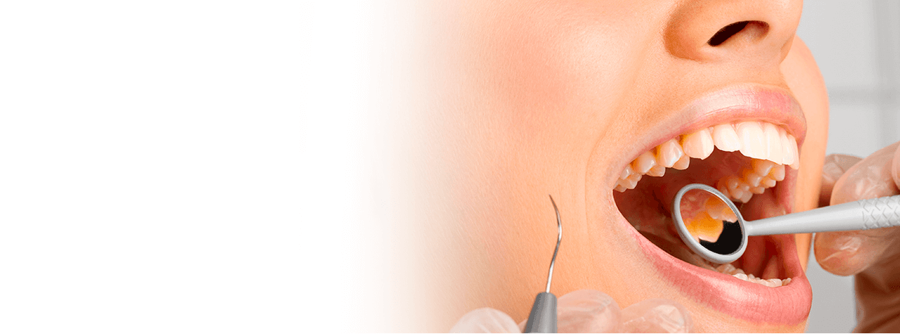 Un dentista che indossa dispositivi di protezione DPI e un camice bianco sorride con compassione