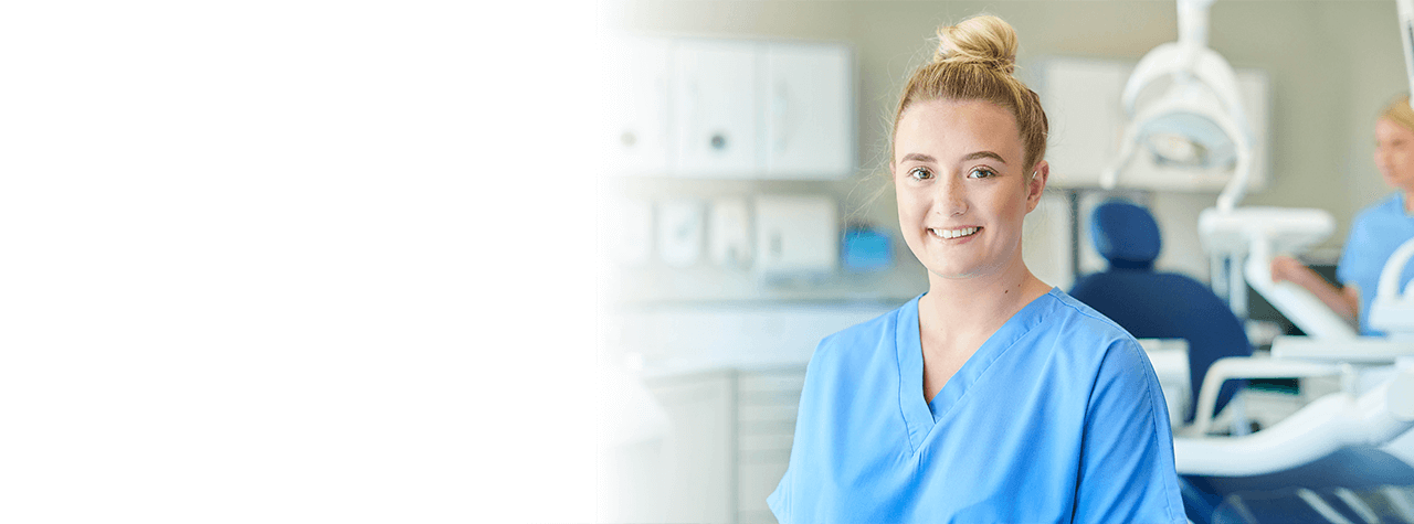 Un professionista dentale che indossa un'attrezzatura di sicurezza DPI e un camice bianco che sorride compassionevolmente